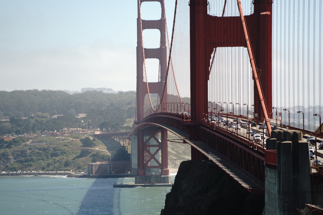 The Golden Gate Bridge from the Marin side, its near tower rising over the headland and traffic crossing the deck