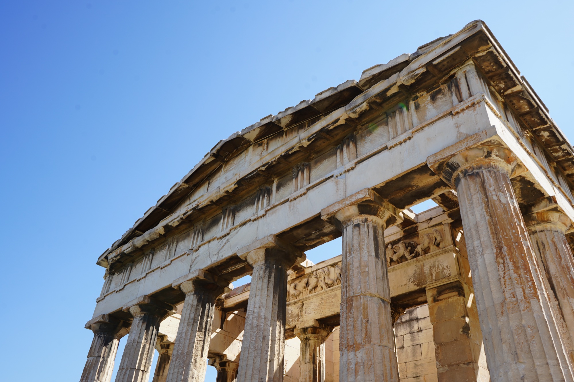 The Temple of Hephaestus from below, Doric columns and frieze against a clear sky
