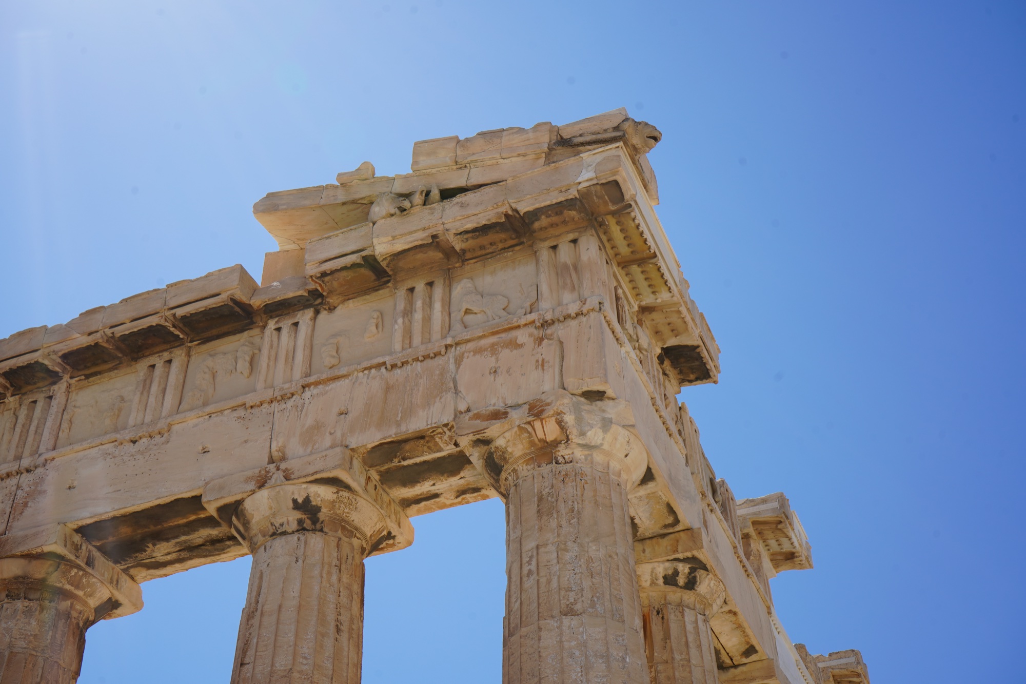 Parthenon columns and entablature from below, restoration blocks pale against the weathered marble