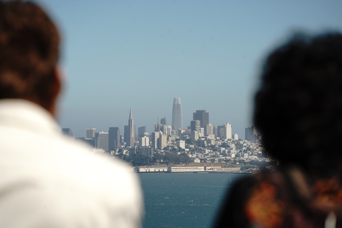 The San Francisco skyline across the bay, framed between the shoulders of two people watching
