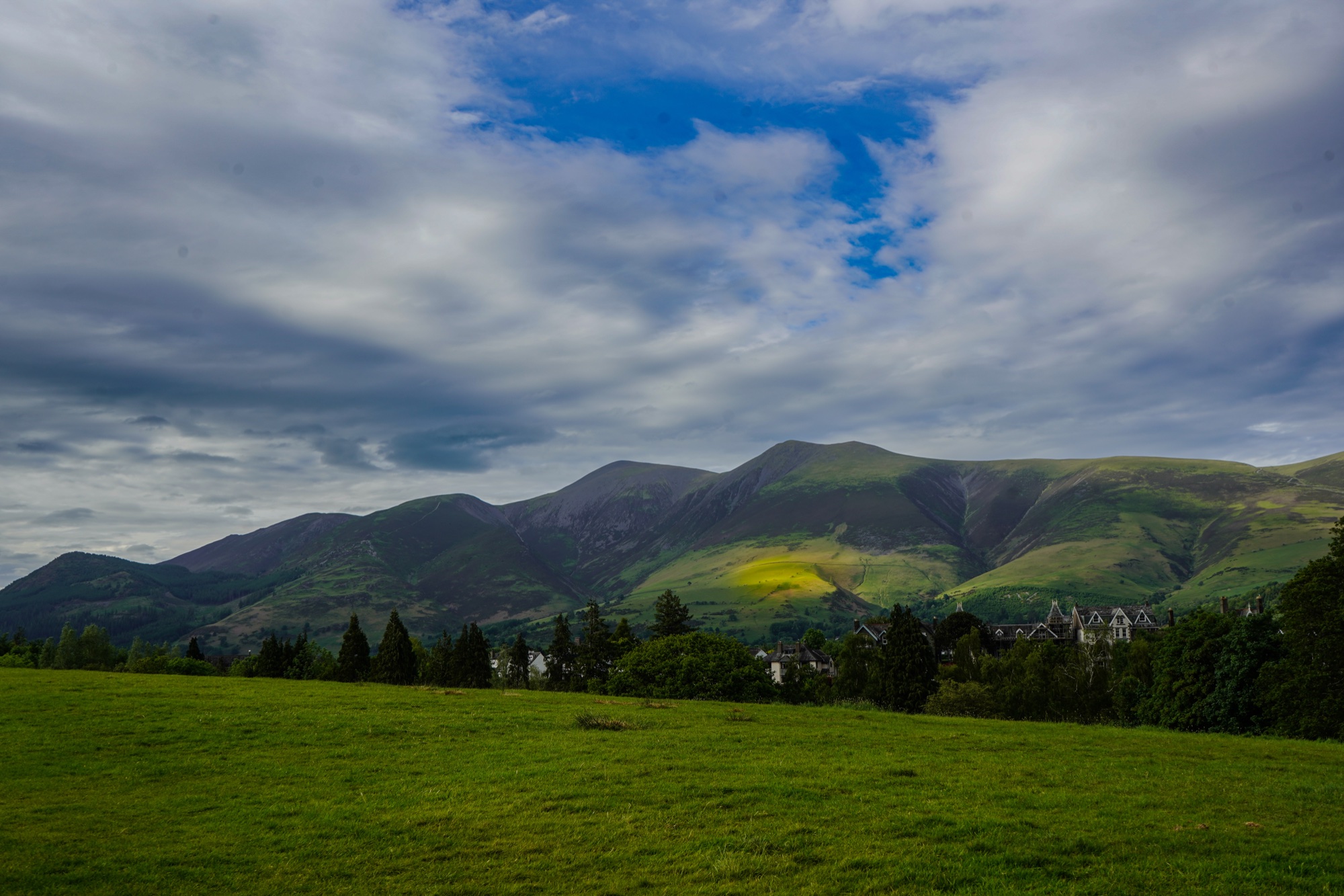 The Skiddaw fells above the rooftops of Keswick, one patch of sunlight moving across the lower slopes