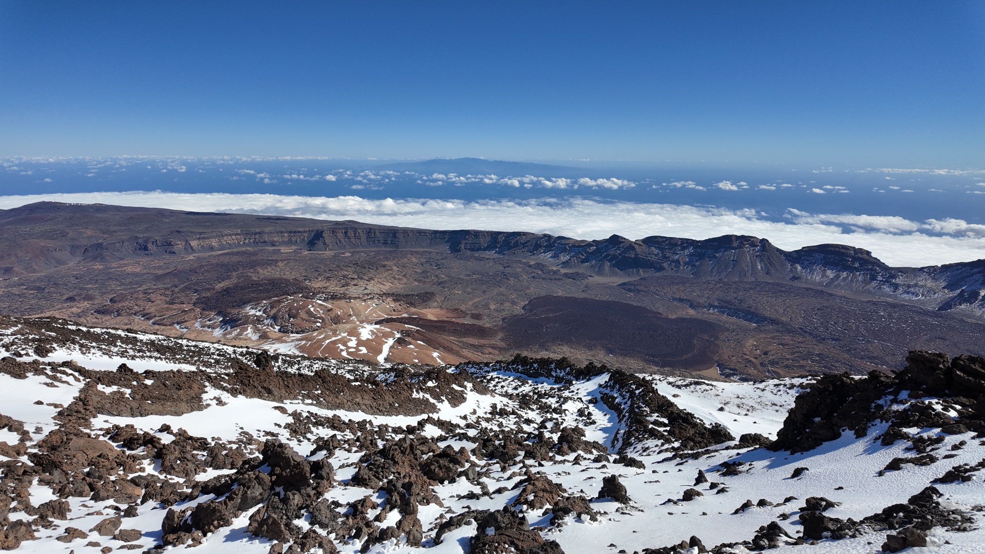 The Las Cañadas caldera from high on Teide, snow in the foreground and a sea of cloud with another island on the horizon