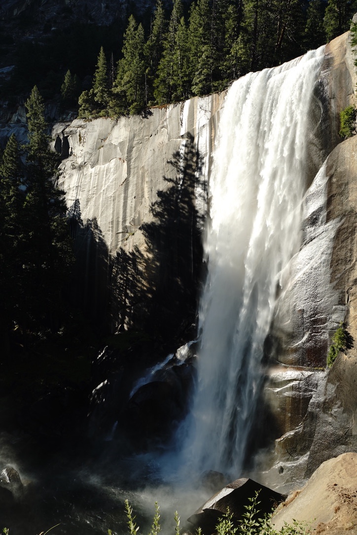 Vernal Fall falling in a wide white sheet down a dark granite cliff